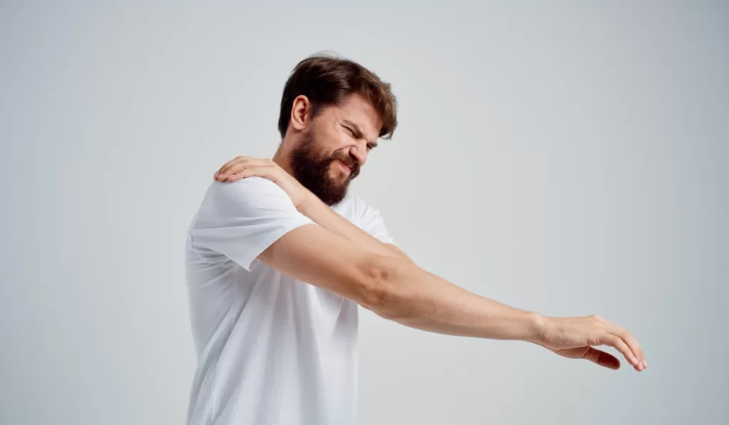 Man holding his shoulder due to stiffness and soreness